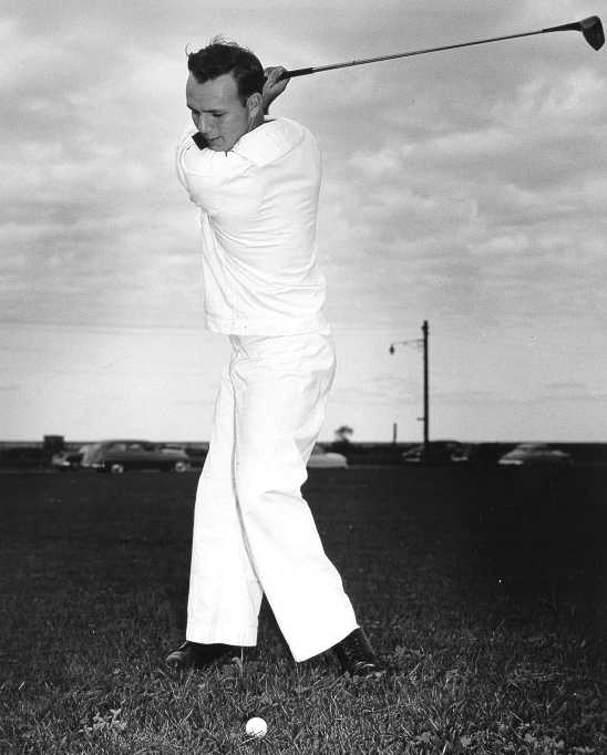 A golfer completing his swing, 1950s-60s black and white photograph