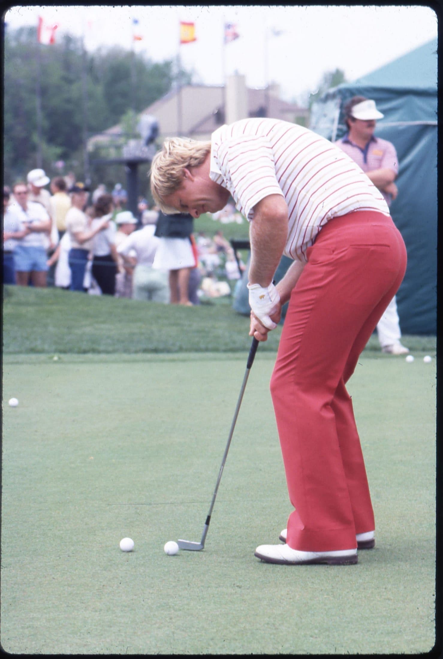 A golfer putting on the green in 1980s tournament attire
